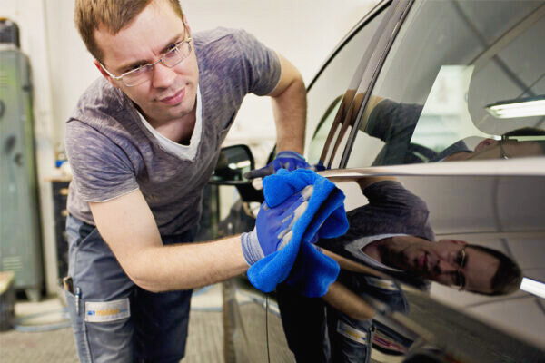 Moldan Mitarbeiter reinigt und poliert die Fahrzeugoberfläche mit einem Tuch