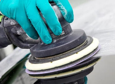 Polierarbeit an einer Fahrzeugoberfläche mit Exzenterpoliermaschine und Handschuhen